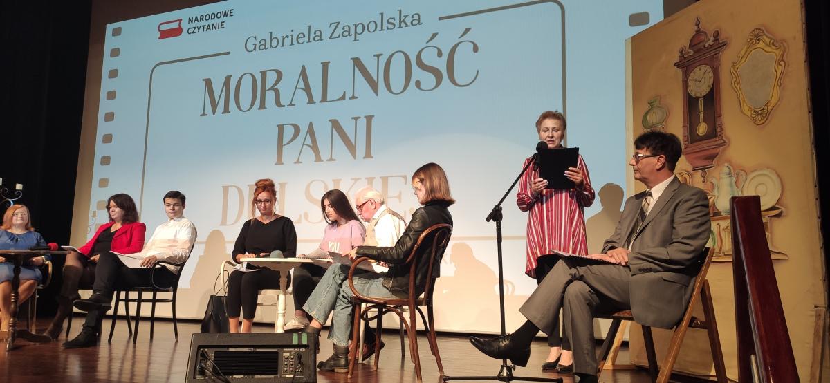 Zdjęcie kolorowe, Narodowe Czytanie Moralności Pani Dulskiej na sali widowiskowej Centrum Kultury i Sztuki w Połańcu, widoczni lektorzy na scenie
