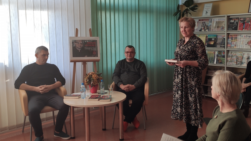 Zdjęcie kolorowe, uczestnicy spotkania z Jarosławem Czechowiczem w Połańcu, na pierwszym planie dyrektor Biblioteki Renata Wójtowicz podczas powitania