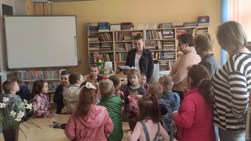 Zdjęcie kolorowe, przedszkolaki z życzeniami z okazji dnia bibliotekarza w bibliotece