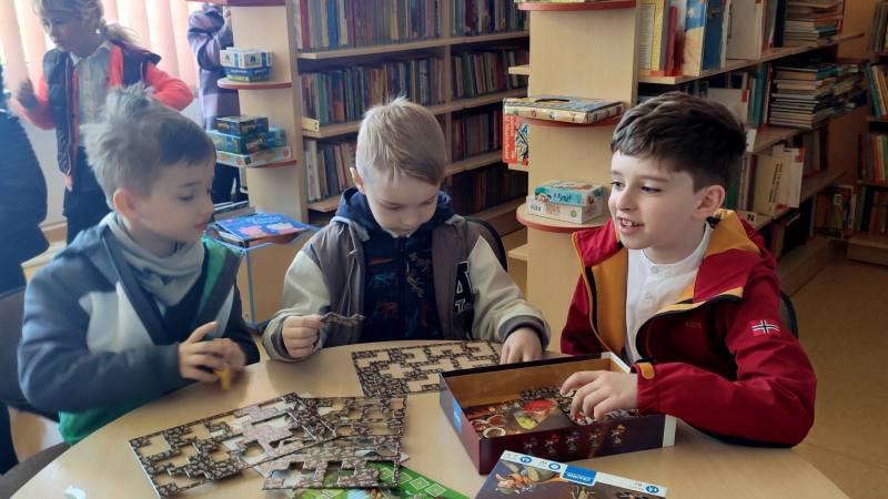 Zdjęcie kolorowe, przedszkolaki z życzeniami z okazji dnia bibliotekarza w bibliotece