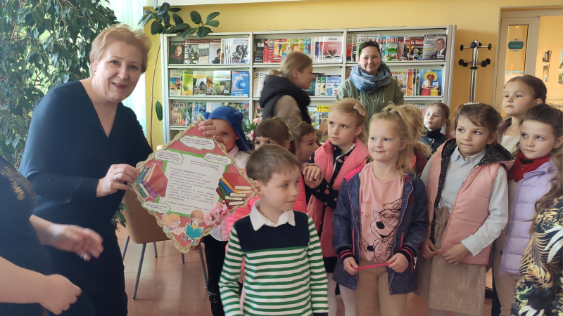 Zdjęcie kolorowe, przedszkolaki z życzeniami z okazji dnia bibliotekarza w bibliotece